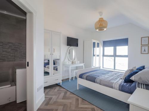 a white bedroom with a bed and a mirror at Rockside in Buckie