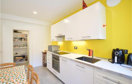 a kitchen with yellow walls and white cabinets and a sink at Stunning Home In Ledro With Wifi in Ledro