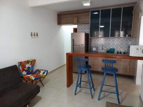 uma cozinha com bancos de bar azuis e um frigorífico em Lindo Apartamento em Lençóis em Lençóis