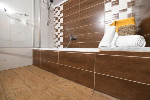 a bathroom with a tub and a shower with brown tiles at Grand Lux Apartment in Serres