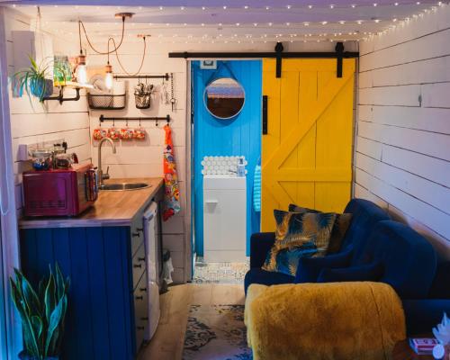 a kitchen with a blue couch and a yellow door at The Horrrsebox Tinyhouse Glamping in Garadice
