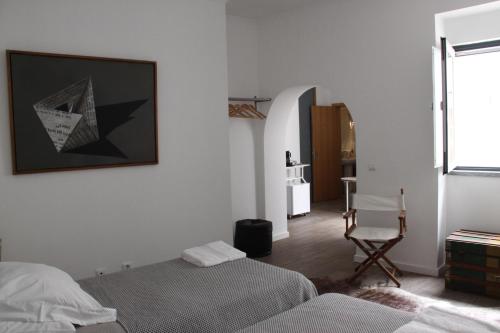 Un dormitorio con 2 camas y una silla. en GALLE - Suite dos Infantes, en Beja