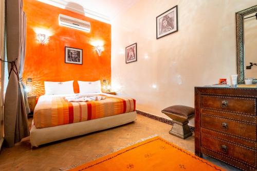 a bedroom with a bed with an orange wall at Riad Kamal Medina in Marrakesh