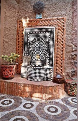 eine Steinmauer mit einem Kamin mit zwei Topfpflanzen in der Unterkunft Maison Ait Mizane in Imlil