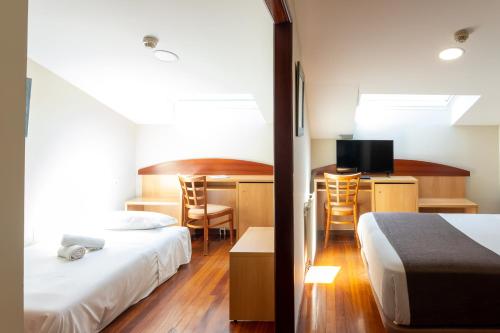 Habitación de hotel con 2 camas y escritorio con TV. en Real Ferrol, en Ferrol