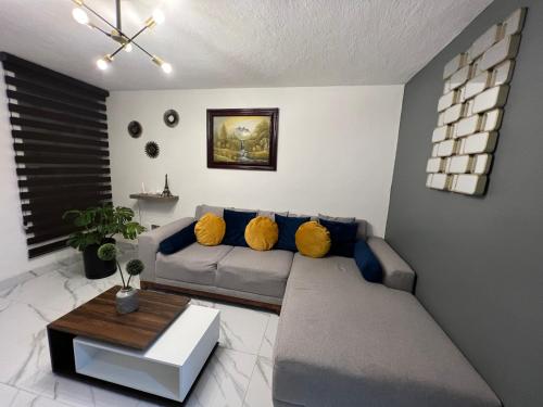 sala de estar con sofá gris y almohadas amarillas en Comfortable apartment with parking, best location, en Guadalajara