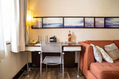 a living room with a couch and a desk and a table at FLAT PRIME COM PISCINA Na REGIÃO DA PAULISTA - JARDINS in Sao Paulo