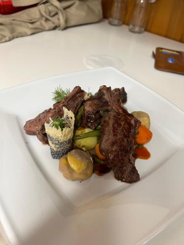 a plate of food with meat and vegetables on a table at Hotel und Restaurant Alpina in Savognin