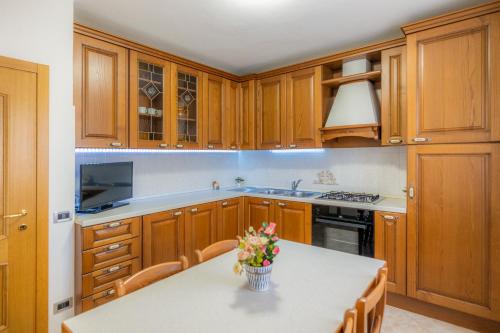 a kitchen with wooden cabinets and a table with flowers on it at [Presolana Home] relax con vista - SELF CHECK IN in Castione della Presolana