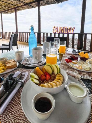 - une table avec une assiette de nourriture et un bol de fruits dans l'établissement Fishermans Resort Life, à La Libertad