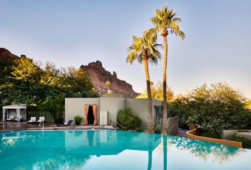 une piscine bordée de palmiers et une maison dans l'établissement Sanctuary Camelback Mountain, A Gurney's Resort and Spa, à Scottsdale