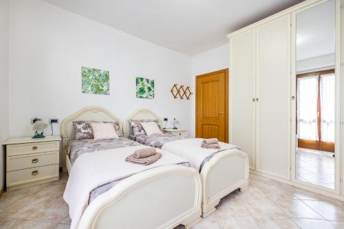 2 łóżka w sypialni z białymi ścianami w obiekcie [Presolana Home] relax con vista - SELF CHECK IN w mieście Castione della Presolana