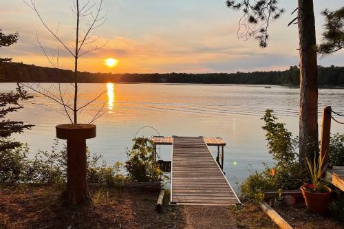 a wooden dock on a lake with a sunset at Cozy Interlochen Cabin with Dock 1 Mi to Green Lake in Interlochen