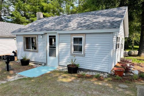 a small white house with a blue door at Cozy Interlochen Cabin with Dock 1 Mi to Green Lake in Interlochen