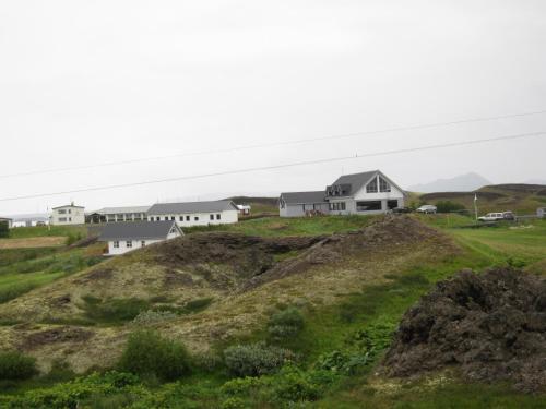 a house on a hill with houses in the background at Skútustadir Guesthouse in Myvatn