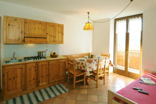 una cocina con armarios de madera y una mesa con sillas. en Casa Anselmi en Croviana