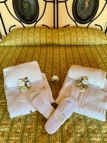 a bed with two white towels and two shoes at Locanda Poggioleone in Castiglione del Lago