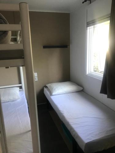 a small room with two bunk beds and a window at Mobil Home D27 in Le Grau-du-Roi