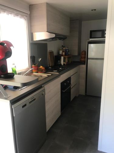 a kitchen with a sink and a refrigerator at Mobil Home D27 in Le Grau-du-Roi