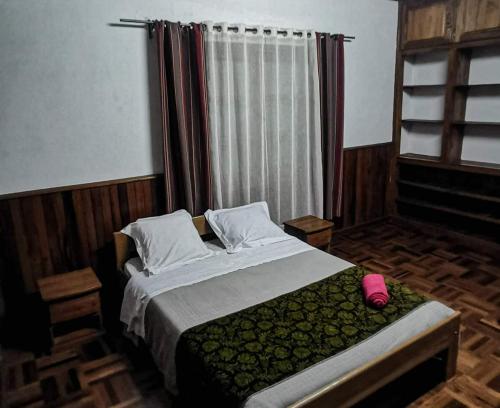 a bedroom with a bed and a window with avertisement at L'anis Etoilé - Hôtel Restaurant in Antsirabe