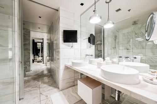 a white bathroom with three sinks and a television at StripViewSuites Two-Bedroom Con-Joined Exclusive Condo in Las Vegas