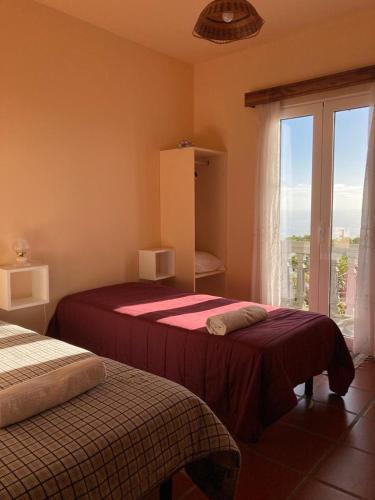 a bedroom with two beds and a window with a view at Casa do Arco in Arco da Calheta