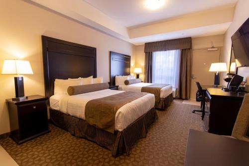 a hotel room with two beds and a desk at Kanata Whitecourt in Whitecourt