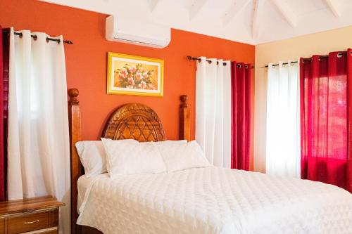 a bedroom with a bed with orange walls and red curtains at PALMS ESCAPE - 3 BEDROOM VACATION HOME in Richmond