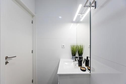 een witte badkamer met een wastafel en een spiegel bij 150 Rivoli Apartments by LovelyStay in Porto