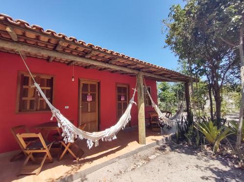 una casa roja con hamacas delante en Pousada Quintal dos Sonhos Xandó Caraiva, en Caraíva