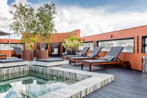 une terrasse avec des chaises longues et une piscine dans l'établissement Victory Business Hotel, à Juiz de Fora