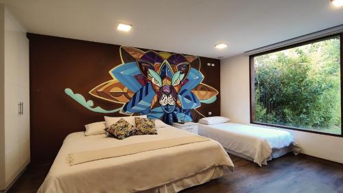 a bedroom with two beds and a painting on the wall at 593 Hotel Boutique Baños in Baños