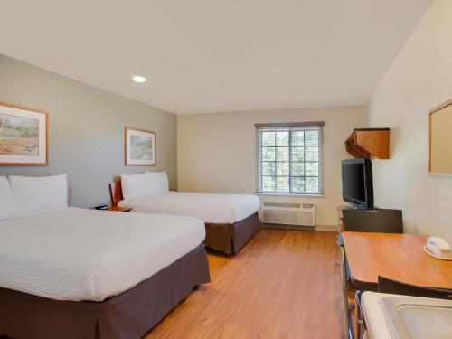 a hotel room with two beds and a desk and a tv at Extended Stay America Select Suites - Tuscaloosa in Tuscaloosa