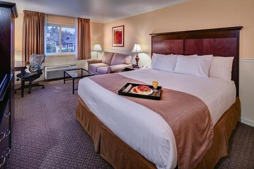 Lake Natoma Inn في فولسوم: غرفه فندقيه بسرير كبير وصاله