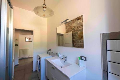 uma casa de banho branca com um lavatório e um espelho em PODERE PRATIZZOLI em Tolè