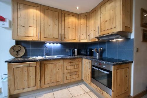une cuisine avec des placards en bois et des comptoirs noirs dans l'établissement Tignes - Duplex spacieux à 2 mn des pistes - 8 pers, à Tignes