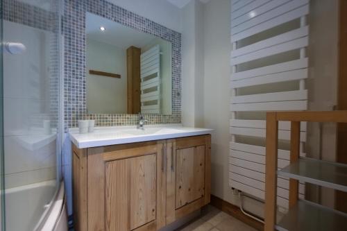 une salle de bain avec un lavabo, une baignoire et un miroir dans l'établissement Tignes - Duplex spacieux à 2 mn des pistes - 8 pers, à Tignes