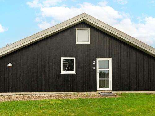 ノーポにある12 person holiday home in Nordborgの白いドアと窓のある黒い家