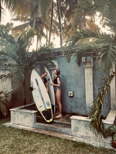 two women in bathing suits standing next to a house with surfboards at Midigama Holiday Inn in Midigama