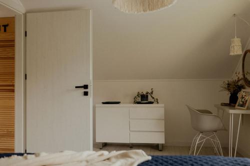 a bedroom with a white cabinet and a chair at Lipa pod groniem in Ustroń