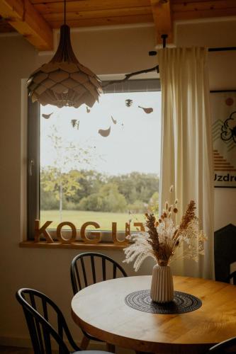 a dining room table with a vase of flowers and a window at Lipa pod groniem in Ustroń