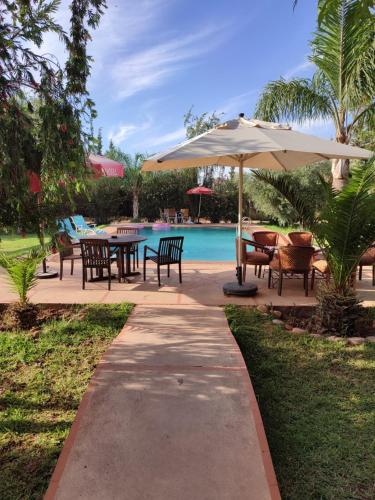 - une terrasse avec des tables et un parasol à côté de la piscine dans l'établissement villa Marrakech raja, à Marrakech