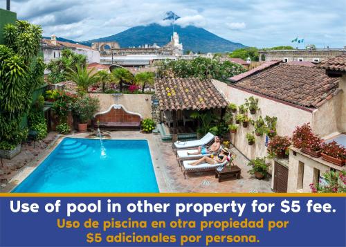 a woman sitting in a chair next to a swimming pool at Hotel Las Camelias Inn by AHS in Antigua Guatemala