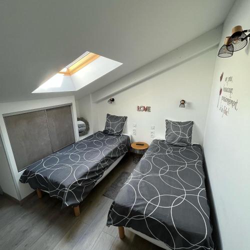 une chambre avec deux lits et une lucarne dans l'établissement Maison chaleureuse avec terrasse privative proche de la gare et du centre-ville, à Rochefort