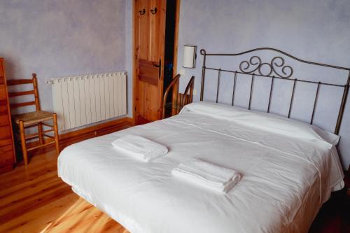 a bed with white sheets and a chair in a room at El Xalet de la Vall de Cardós in Lladrós