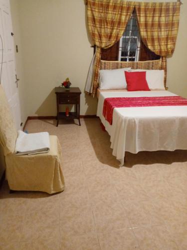 sypialnia z łóżkiem, oknem i krzesłem w obiekcie Inviting 2-Bed House in Fair Prospect w mieście Port Antonio