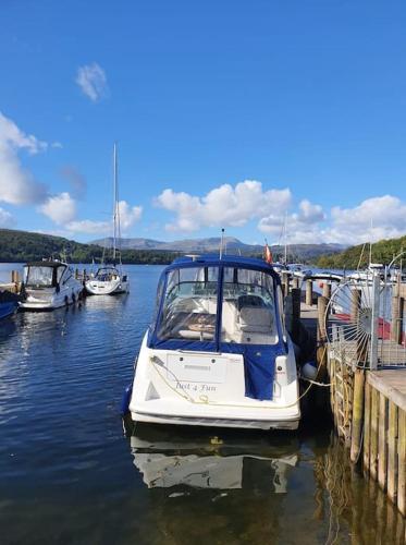 a small boat tied to a dock in the water at Jaw-Dropping Lodge with Hot Tub on Lake Windermere in Windermere