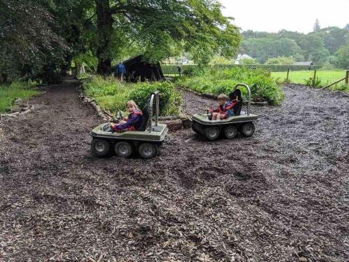 two children riding on toy cars on a playground at Jaw-Dropping Lodge with Hot Tub on Lake Windermere in Windermere