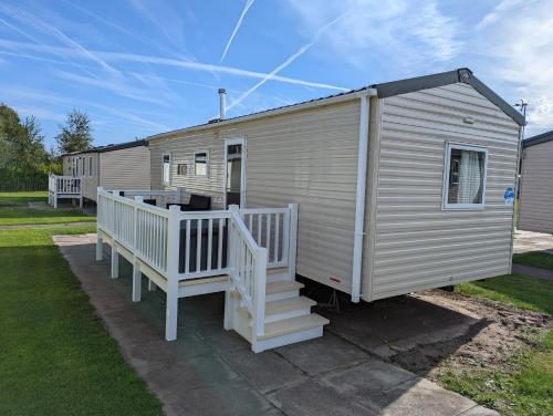 a large white mobile home with a porch and stairs at The Jones's Family Caravan with private decking - Presthaven in Prestatyn
