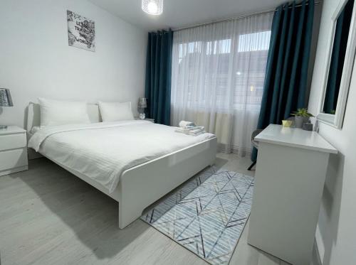 a white bedroom with a large bed and a window at Inga Apartment in Turda